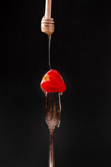 Strawberries on a fork with dripping honey