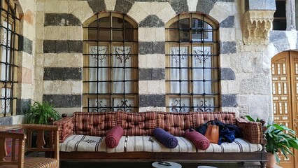 Closeup of an oriental sofa with long pillows on beautiful windows with bars background - obrazy, fototapety, plakaty