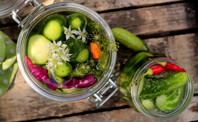 pickles in a jar with bitter pepper and inflorescence of wild garlic on a wooden surface selective focus, fermented vegetables