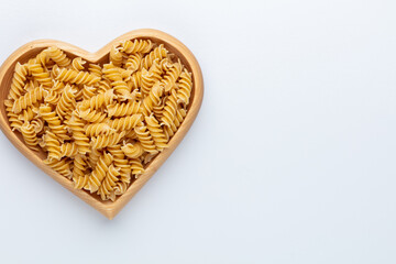 Pasta in a heart shaped wood bowl.