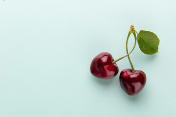 Obraz na płótnie Canvas Cherry berries on a pastel background top view. Background with a cherry on a sprig, flat lay