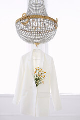 white jacket on hanger with bouquet of daisies on the chandelier 