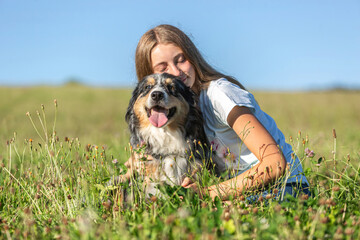 Cute friendship scene between a teenage girl and her australian shepherd dog in summer outdoors....
