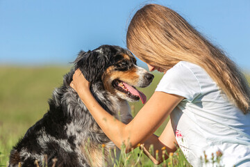 Cute friendship scene between a teenage girl and her australian shepherd dog in summer outdoors....