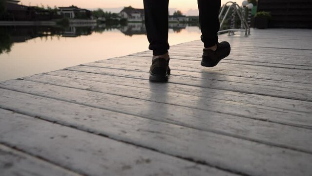 Low angle view of the feet of a man walking on a wooden deck