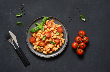 Pasta with tomato sauce and cherry tomatoes on a concrete background, top view, with space for text