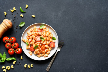 Pasta with tomato sauce and cherry tomatoes on a concrete background, top view, with space for text