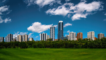 Fototapeta na wymiar Edmonton skyline and cityscape with dramatic clouds over Victoria Park's green in the Province of Alberta, Canada