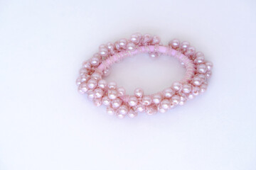 beautiful bracelet made of pink pearls, elastic band, scrunchie on a white background close-up, the...