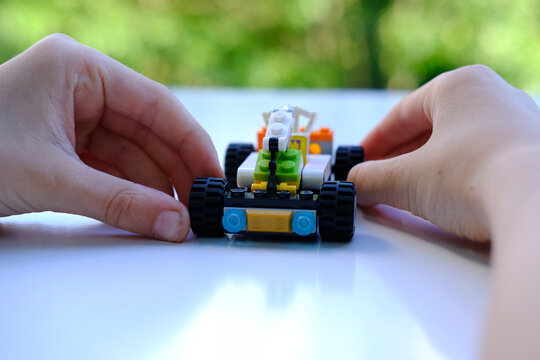transformer car with a manipulator, assembled from lego parts, beautiful green background of trees with bokeh, concept of development of fine motor skills, creativity, children's entertainment
