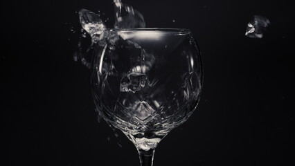 Ice cubes lemons falls empty wineglass closeup. Refreshing drink concept
