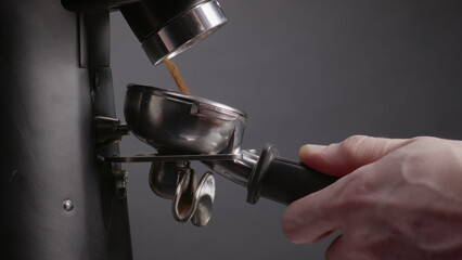 Ground coffee pouring portafilter for coffeemaker closeup. Hand holding filter.