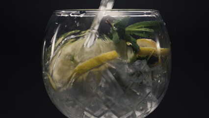 Jet water filling lemon mint wineglass closeup. Preparing homemade drink concept