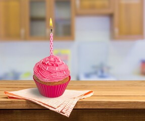 Celebration birthday cupcake with birthday candle and sprinkles on a background