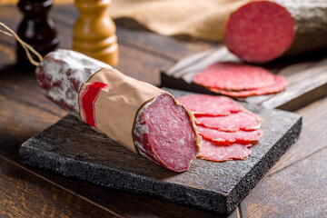 Sliced european sausage on the board on wooden table macro close up