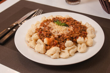 Detail view of a plate of gnocchi with sauce and grated cheese.