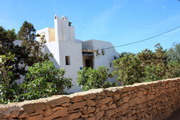 beautiful square typical traditional Ibizan pitiusa white house with arid climate, local vegetation and stone walls