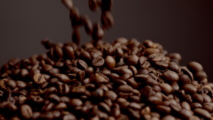 Fresh coffee grains spilling on pile close up. Roasted beans falling down.