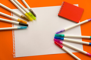 Creative kids, concept. Colorful crayon paints and blank notepad on orange color background markers, red little notepad. Empty paper for painting, space, template. Education, Back to School concept.