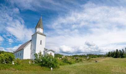 Fototapeta na wymiar St. Matthew's church, built in 1880, guards over the surrounding hilly cemetery in the small village of Green's Harbour, Newfoundland.