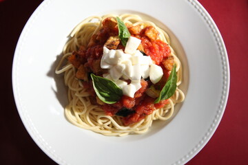 italian spaghetti dish with tomato sauce, fresh mozzarella cheese and basil close up top view