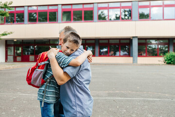 Happy dad hugs the child of the schoolboy and escorts him to school at the beginning of the...