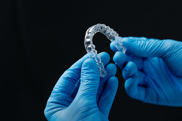 Invisible orthodontics cosmetic aligners in hands of doctor