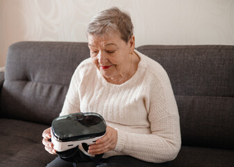 An elderly woman is looking at virtual reality glasses. Modern technologies. New experience in old...