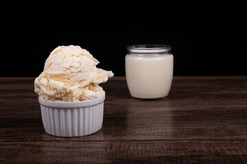 Tasty White cream flavored ice cream. Served in a white pot with a glass of white milk in the background.