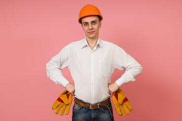 a young man in a white shirt and helmet put his hands on his belt and stands against a pink background