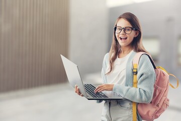 Portrait of smiling teen girl using a laptop computer, studying online