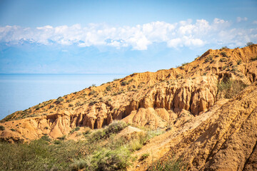 Fototapeta premium Fairytale canyon, Kyrgyzstan, Silk Road, Central Asia, red rocks, colourful, Yssykkul lake in background