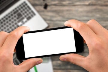 Human holding a smartphone with  screen on table. Office environment.