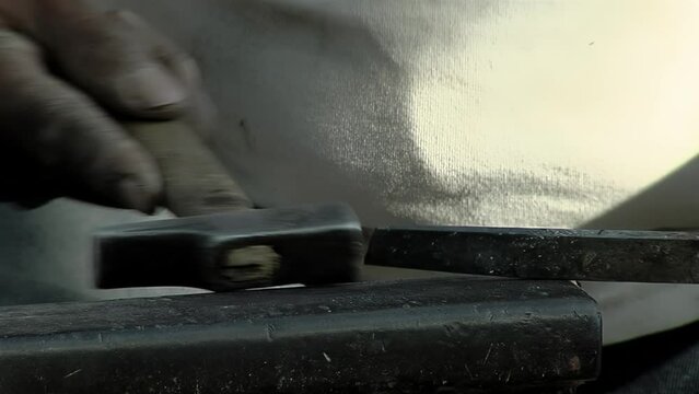 Metalwork, Blacksmith using a Hammer and an Anvil Shaping an Iron Bar. Close Up.