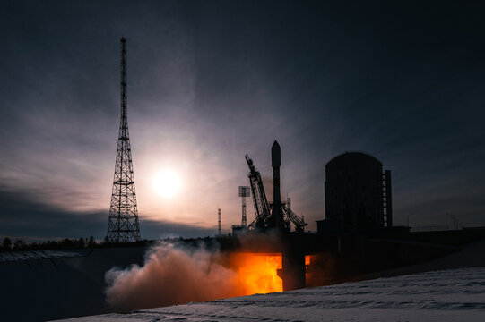 space rocket launch in winter - silhouette lit by fire and sun