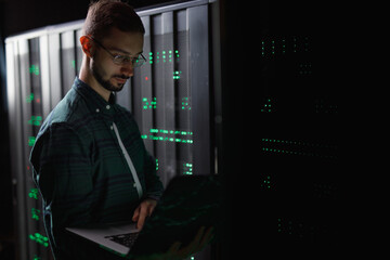 Male employee verifying connection in data centre 