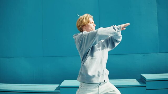 Young man dancing hip hop. Modern dance choreography. Professional breakdancer training on blue background, dancer showing dance movings outdoor. Musical video.