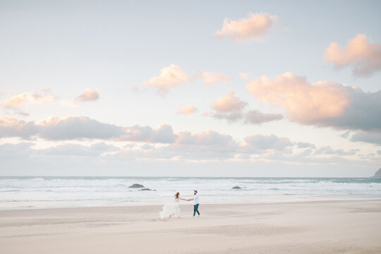 Newlyweds Holding Hands On A Seashore