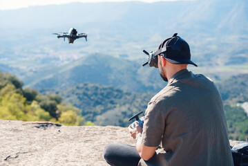 Man controlling UAV on cliff edge in highlands