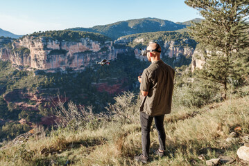 Male FPV drone operator using controller in mountains