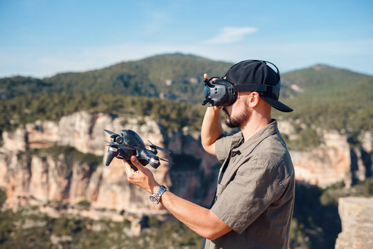 Man in VR glasses launching FPV drone in highlands