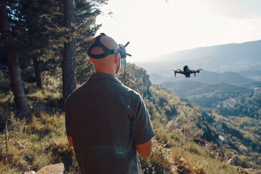 Man standing on mountain slope in front of flying UAV