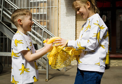 Two kids with bananas on a street