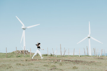 Gen Z girl running surrounded by eolic electric energy powered windmills, new power resources...