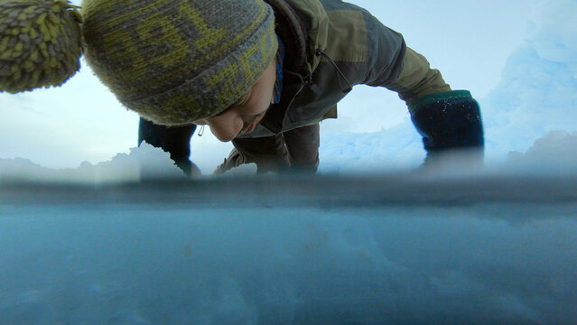 Indigenous Inuit, Inuk, Eskimo hunter at ice fishing hole meniscus