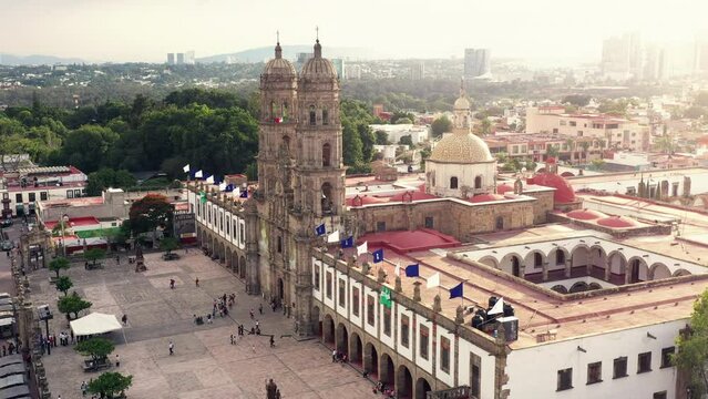 Vuelo drone sobre plaza de las americas con la basilica de zapopan de fondo templo iglesia convento con turistas desconocidos pasando caminando  sobre explanada