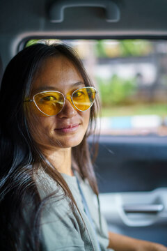 Portrait of Asian woman with sunglasses on in car