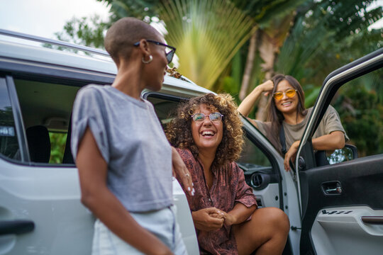 Three friends taking break by talking around car