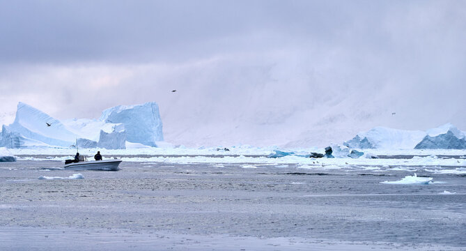 Greenland, Arctic winter: Inuit hunters - fishermen in boat, icebergs