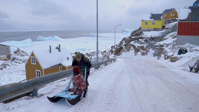 Uummannaq Greenland authentic daily life: father & daughter, sled ride